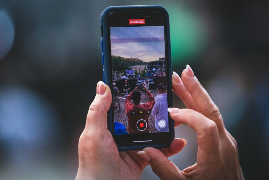 mobile phone held by hand, showing filming of an event stage