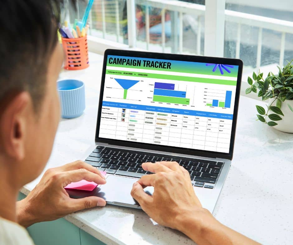 Man looking at laptop screen with words 'Campaign tracker' on and graphs below