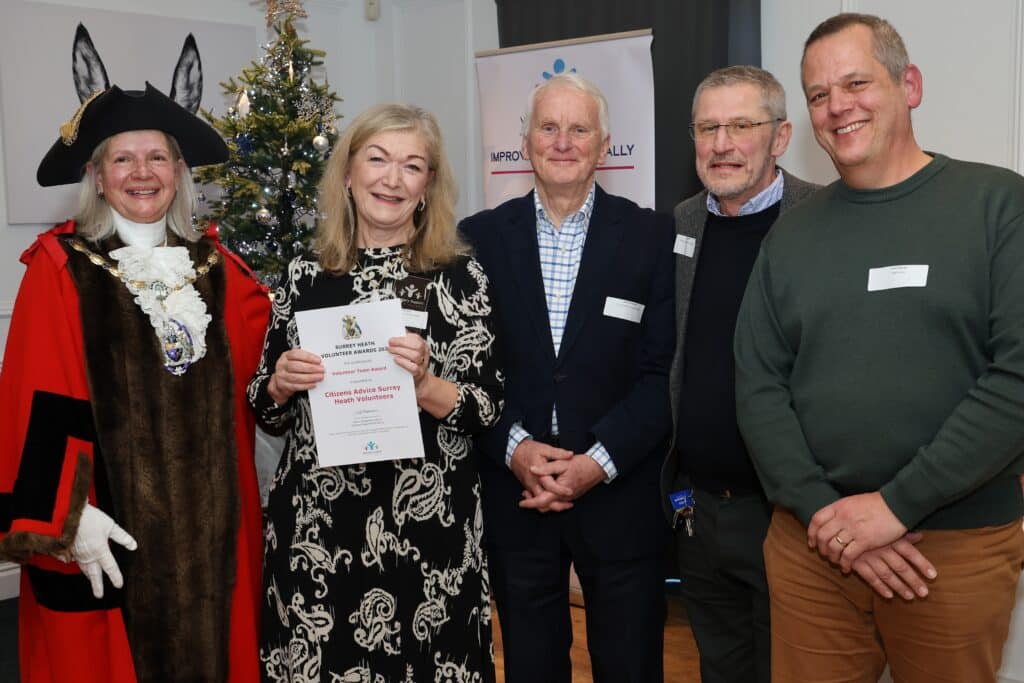 Volunteer team pictured with Surrey Heath mayor in red and black robe and black tricorn.